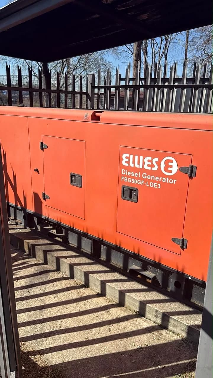 Orange Ellies diesel generator behind a black palisade fence