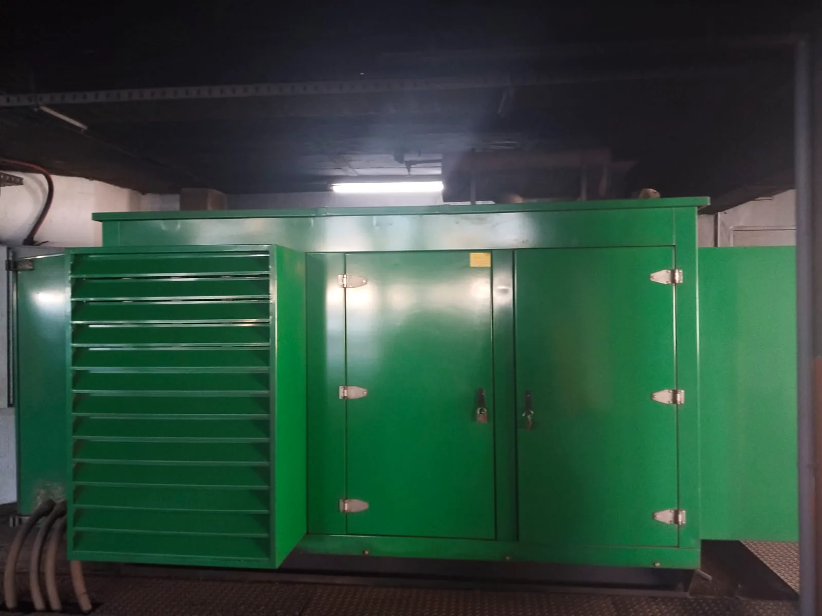 Green canopied diesel generator in an underground parking and plant area