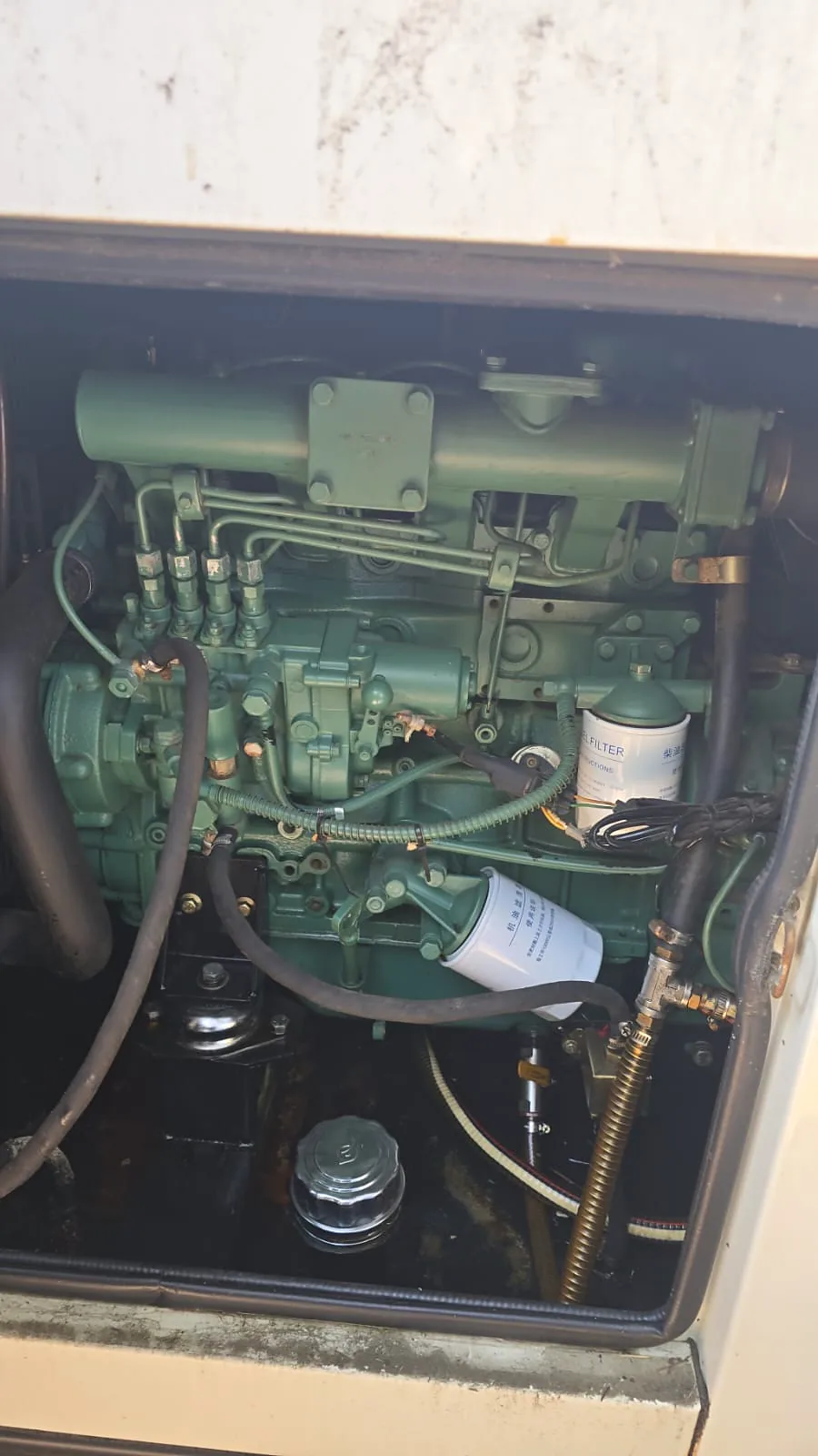 Diesel engine inside a generator canopy, showing the oil filter, fuel filter and fuel lines