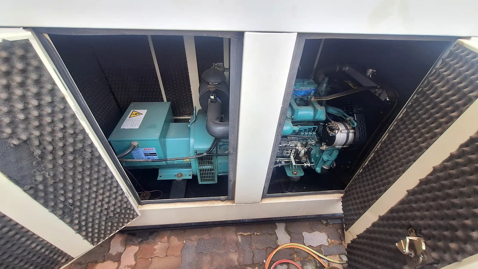 Alternator and diesel engine of a generator set inside an acoustic canopy, with both service doors open