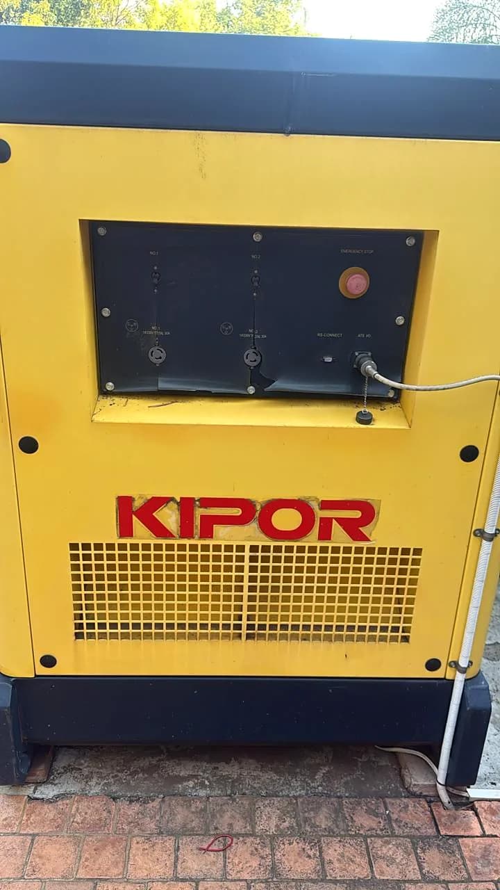 Yellow Kipor diesel generator canopy with its control panel window and emergency stop